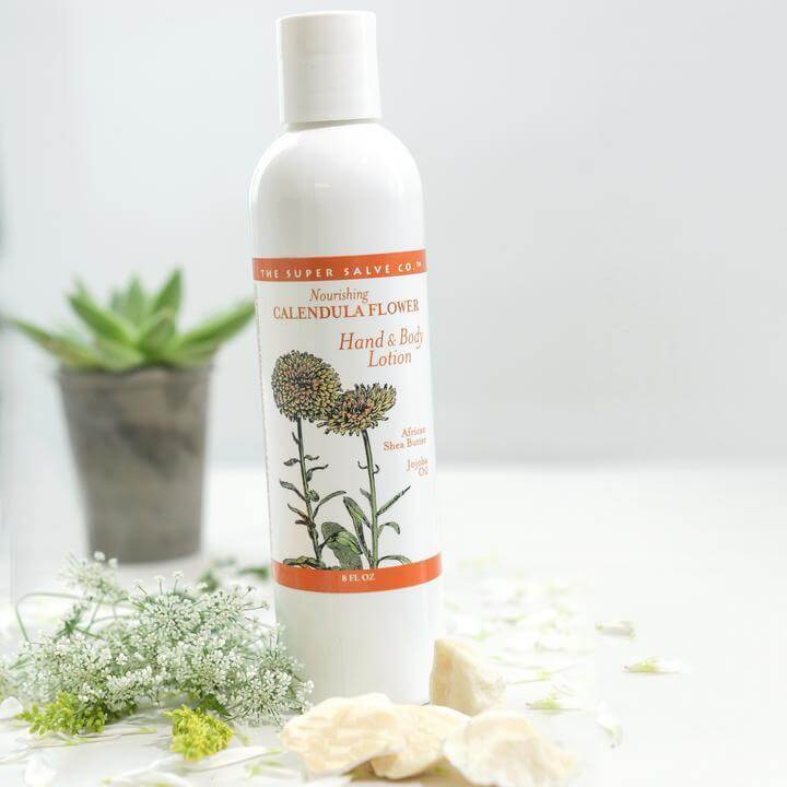 Calendula Flower Lotion 16 oz. set next to some beautiful plants with a pristine white background.