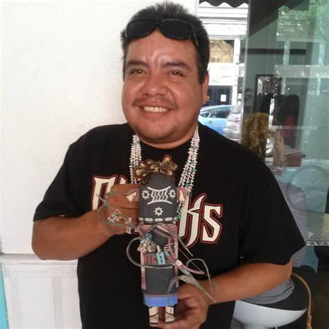 Larry Melendez poses for a photo at Winter Sun with a Kachina doll he carved
