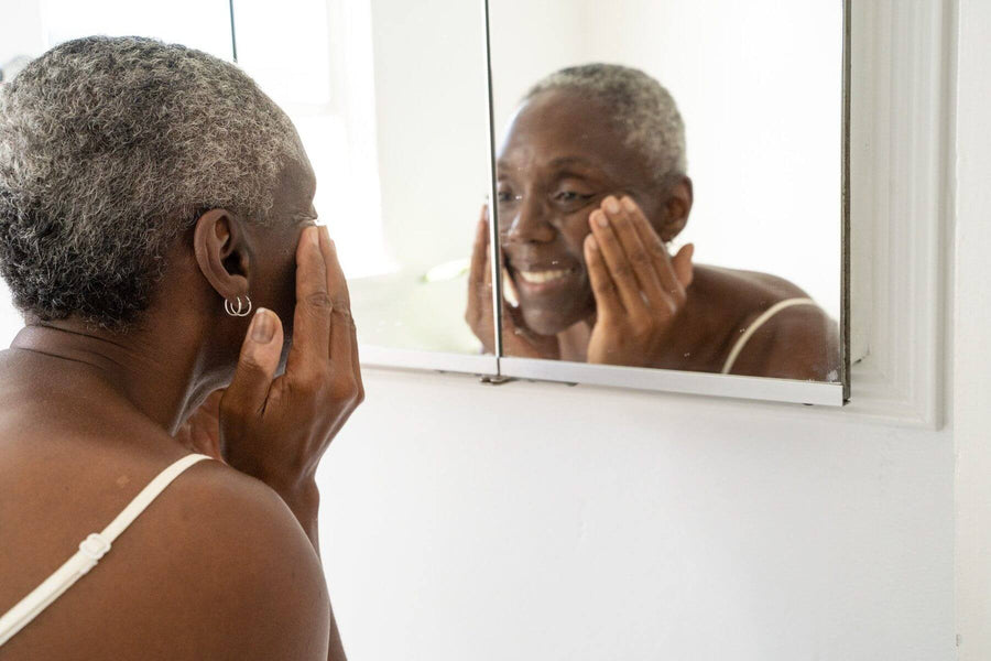 A beautiful woman rubs the coconut cleansing milk onto her face while smiling.