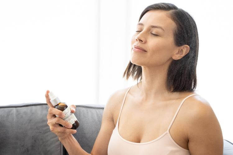 A beautiful woman looks calm and serene while spraying organic rose phyto facial mist onto her face.