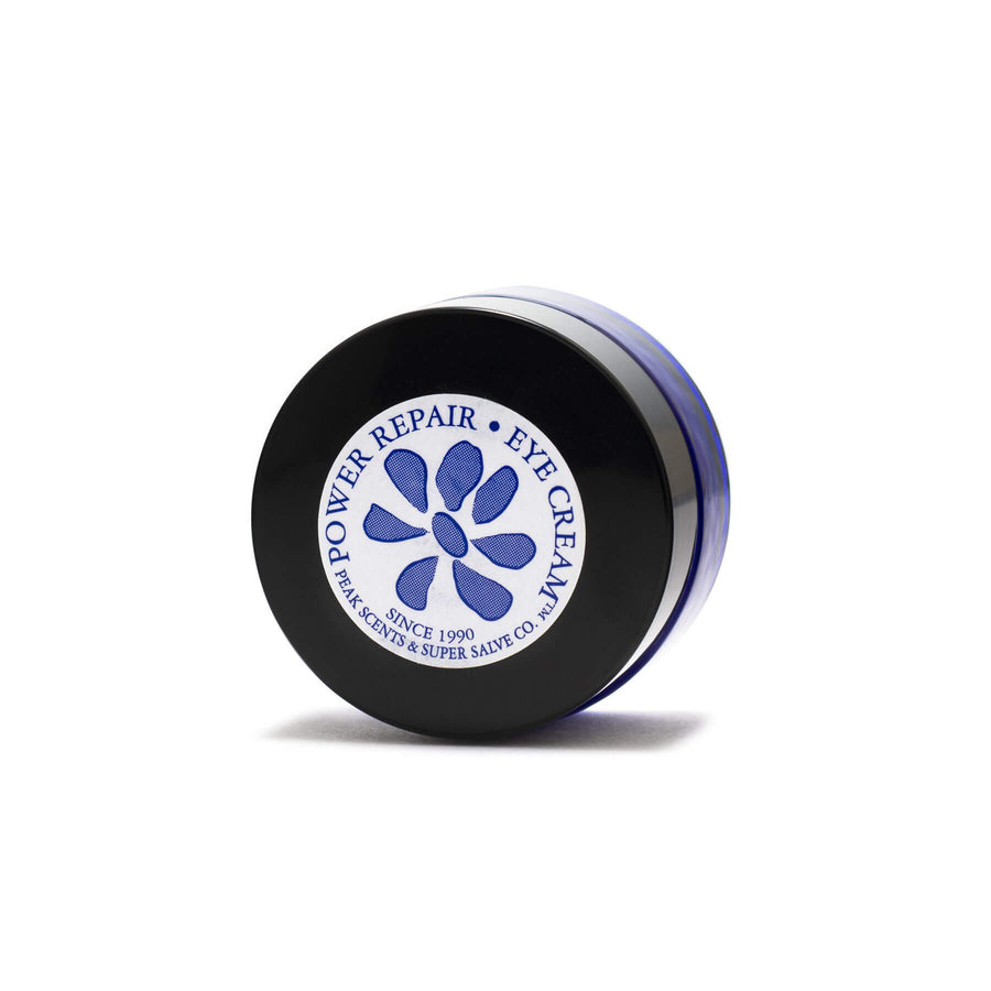A 0.5 oz. container of Power Repair Eye Cream by Peak Scents and Super Salve Co. in a round blue glass container