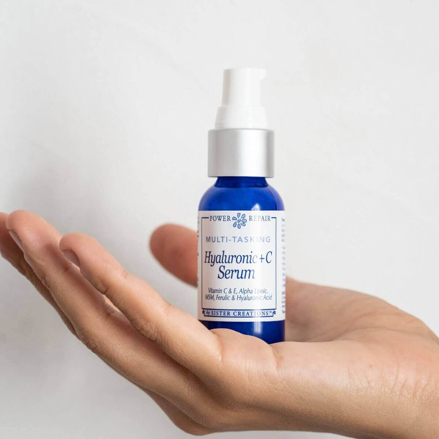 A blue 1 oz. pump bottle of Power Repair Hyaluronic + C Serum is seen in a woman's hand