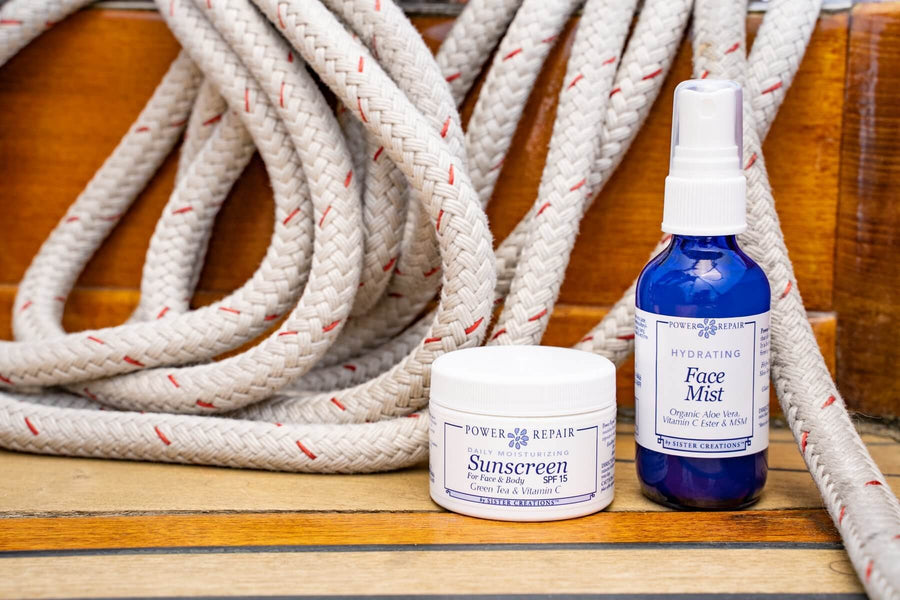 The Power Repair Face Mist and Power Repair sunscreen are sitting on the deck of a boat, ready to be used in an adventure.
