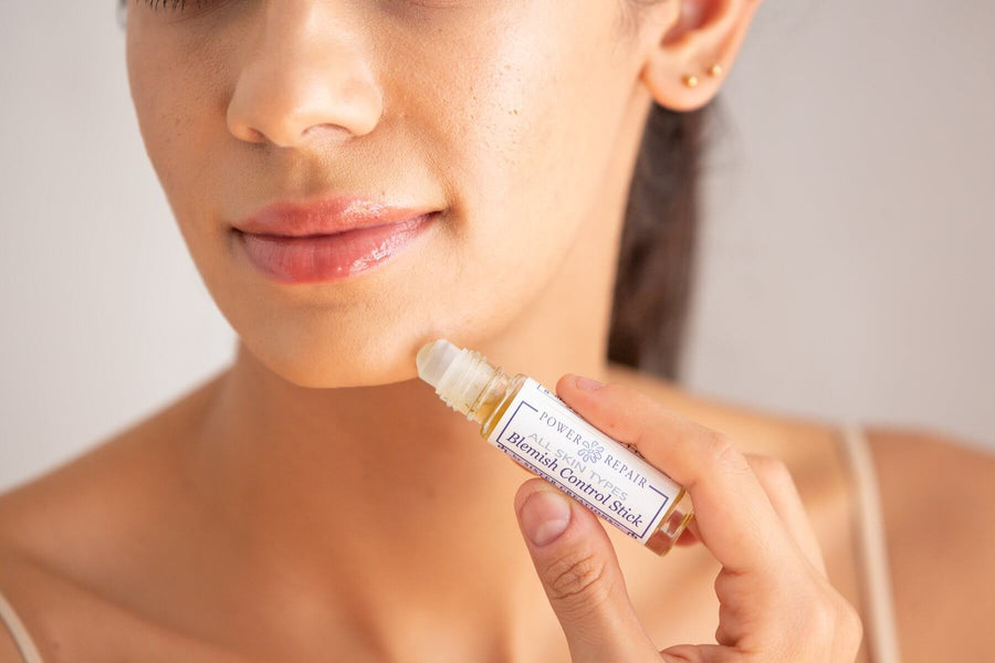 A woman using Power Repair Blemish Stick by Sister Creations on her chin.