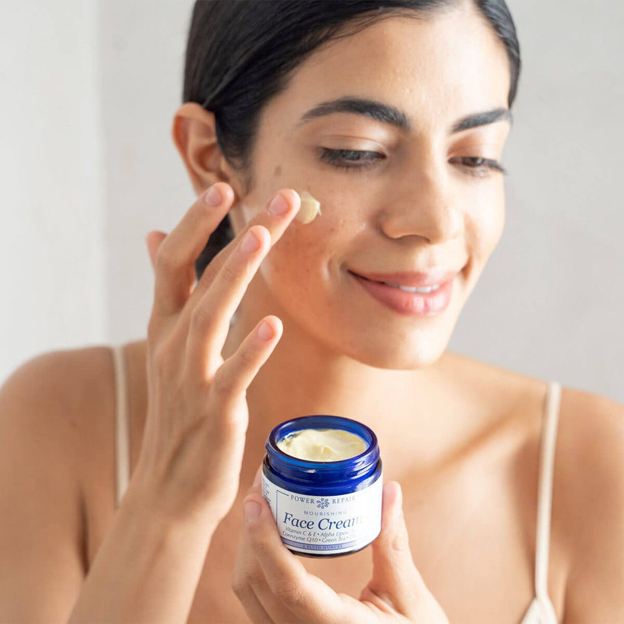 A woman enjoys the sensation of gently rubbing Power Repair Face Cream on her cheek
